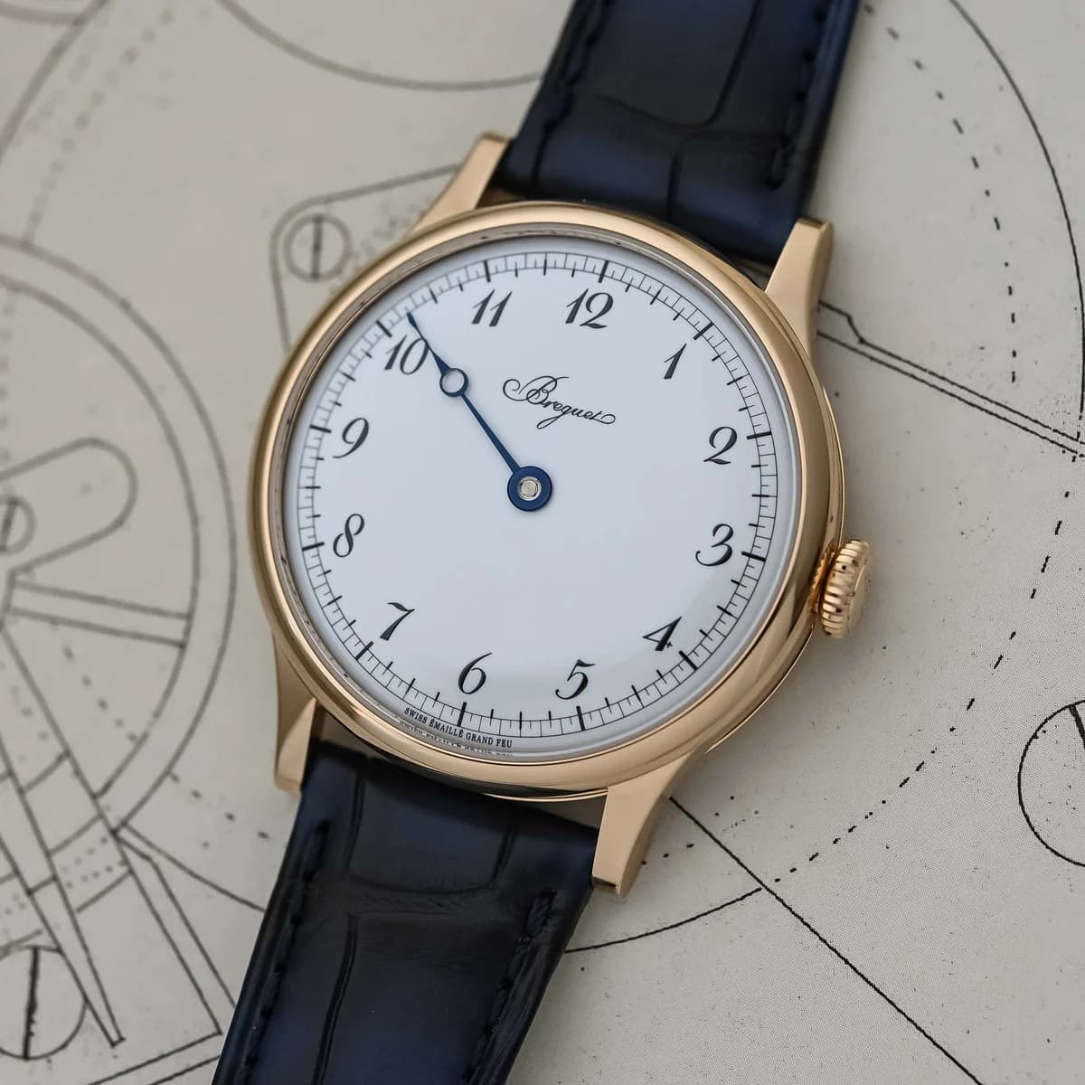 Three-quarter view showing the warm Breguet gold case and navy alligator strap against the original souscription prospectus