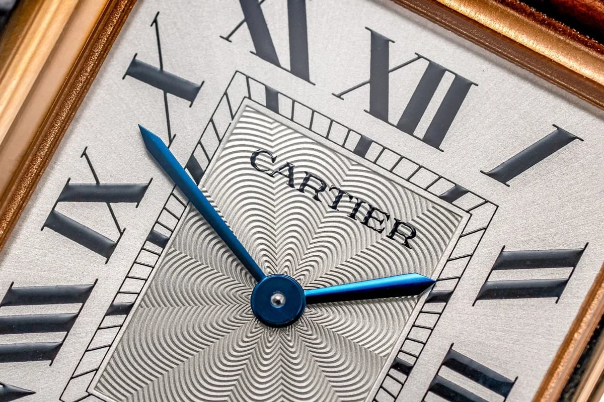Three-quarter view highlighting the crown side. The beaded crown with its cabochon-cut blue sapphire is a direct connection to Cartier's identity as a jewelry house.