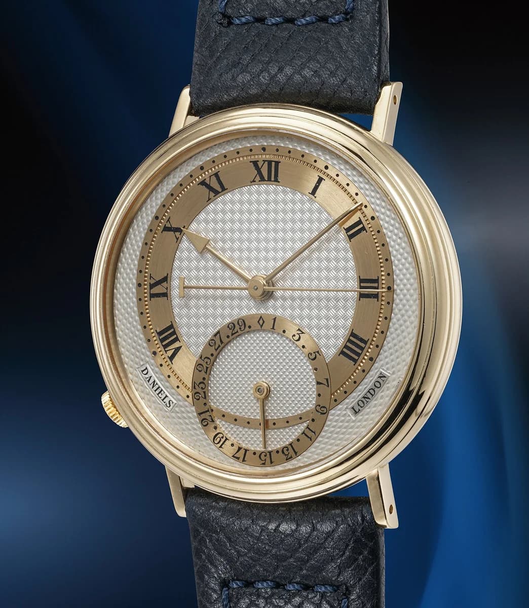 Side profile from the crown side showing the gold winding crown positioned between the lugs.