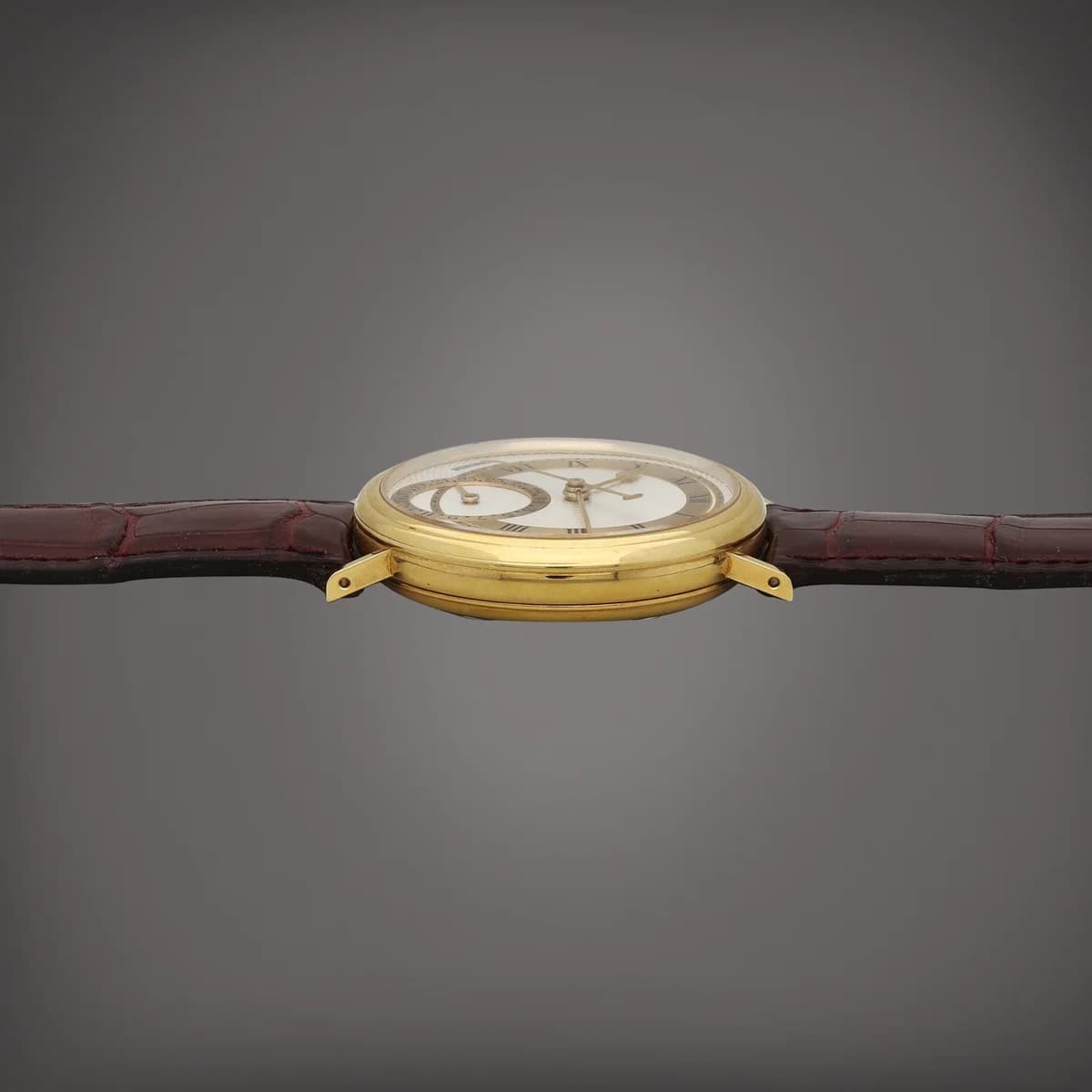 Three-quarter view showing the polished gold case, wire lugs, and the transition from bezel to crystal.