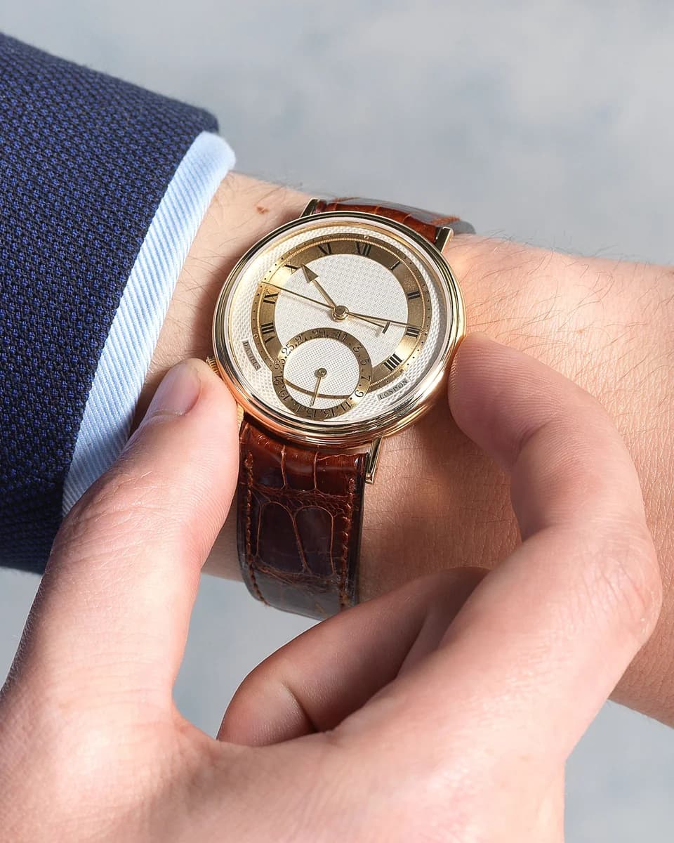 Movement of the white gold variant through the exhibition caseback. The engraving reads Roger W. Smith, Daniels, and Co-Axial Escapement.