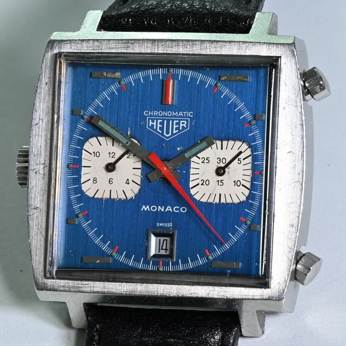 Macro of the dial center showing the white subsidiary registers, squared-off steel hands with luminous inserts, and the red chronograph seconds hand.
