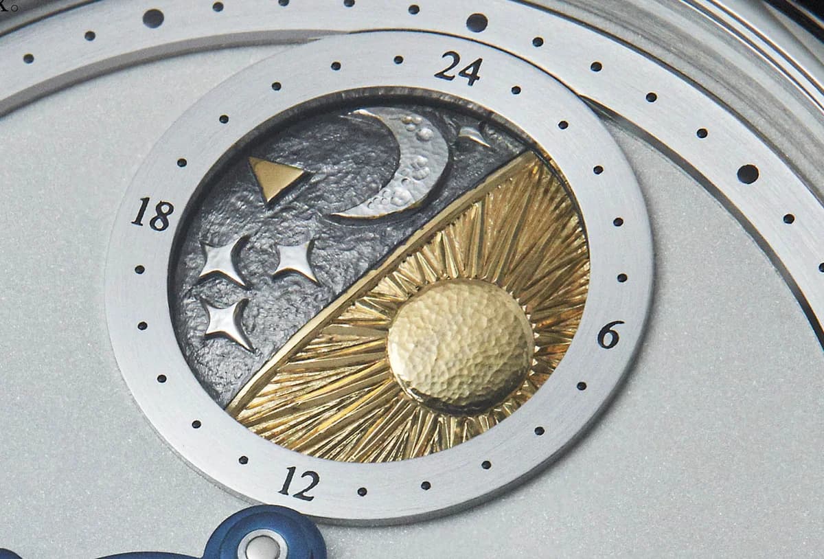 The hand-engraved balance cock with its floral motif and subtle infinity symbol, cut one stroke at a time with a burin