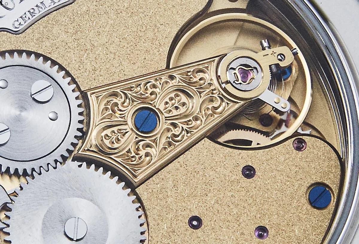 Closer view of the movement through the sapphire caseback showing the three-quarter plate and gear train