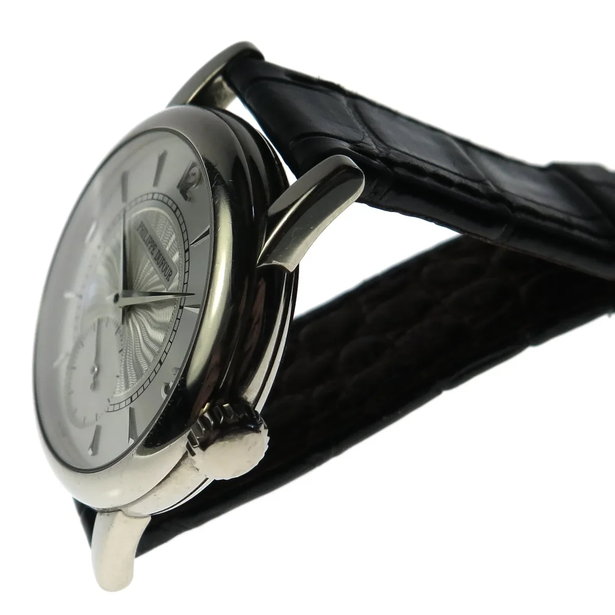 Three-quarter view showing the polished case, guilloche dial texture, and crown profile.