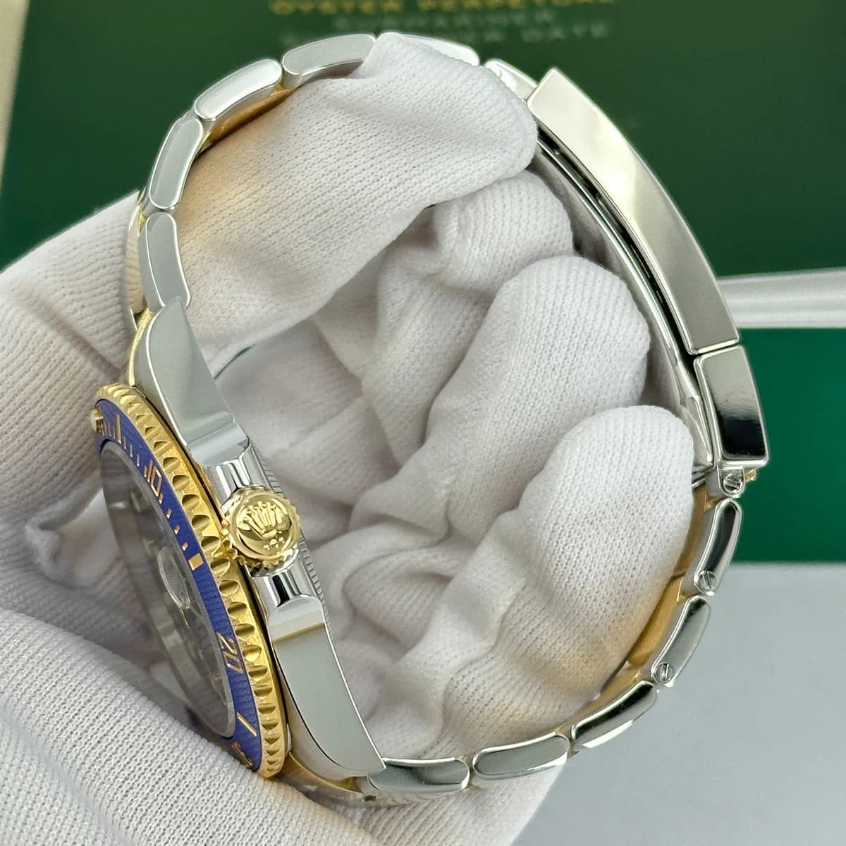 Side profile: gold crown guards, steel case flanks, Cerachrom bezel ring