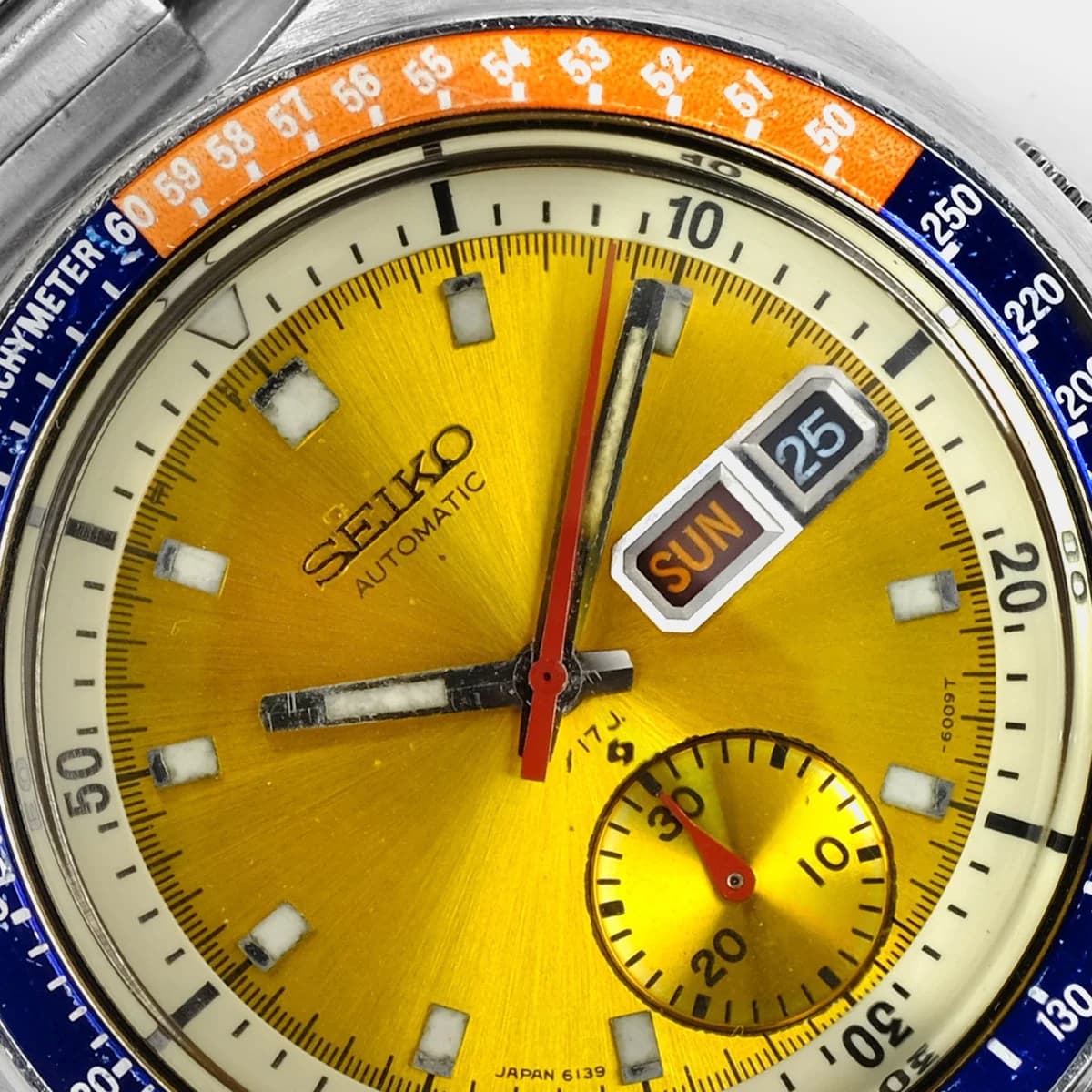 Crown and pusher detail. The single crown controls time setting, day-date quickset, and an internal rotating bezel.